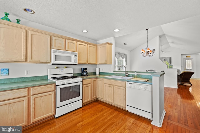 kitchen with white appliances, a sink, light brown cabinetry, healthy amount of natural light, and lofted ceiling