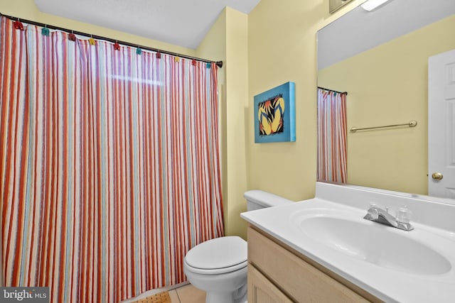 bathroom with toilet, vanity, and tile patterned floors