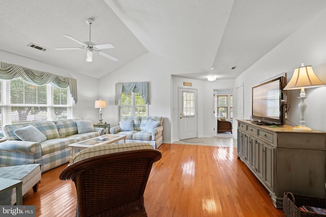 living room with vaulted ceiling, plenty of natural light, a ceiling fan, and light wood-type flooring