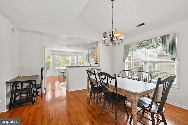 dining area with lofted ceiling, a chandelier, wood finished floors, and baseboards
