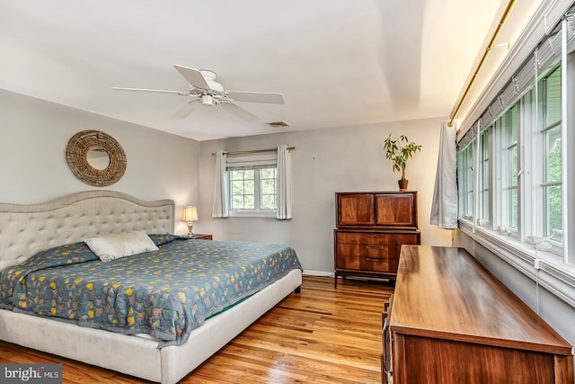 bedroom with light wood-style flooring, ceiling fan, and baseboards