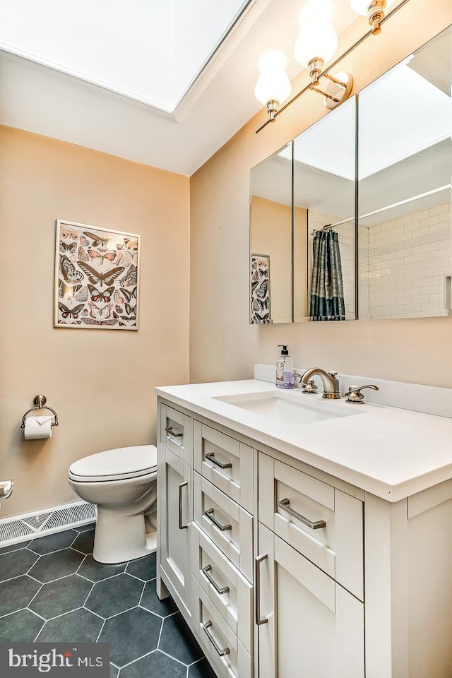 bathroom featuring toilet, tile patterned floors, vanity, and a skylight