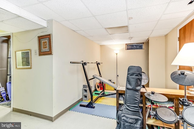 exercise area featuring a drop ceiling, tile patterned floors, and baseboards