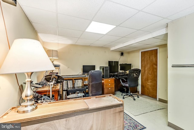 office space featuring a paneled ceiling and baseboards