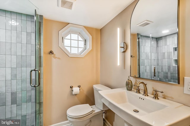 bathroom with a stall shower, toilet, baseboards, and a sink