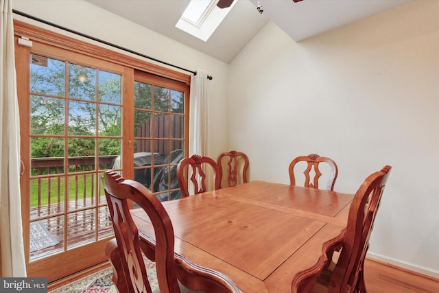 dining area with lofted ceiling, a skylight, wood finished floors, ceiling fan, and baseboards