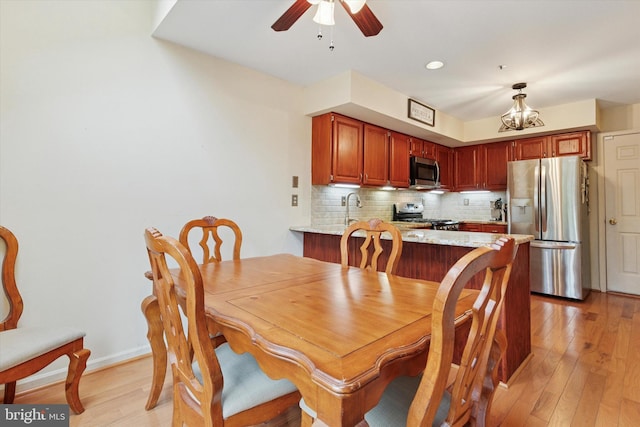 dining room with light wood-type flooring, ceiling fan, and a chandelier