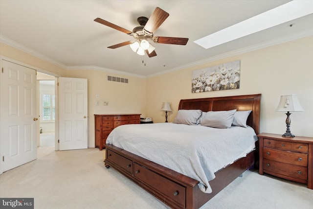 bedroom featuring light colored carpet, ornamental molding, a skylight, and a ceiling fan