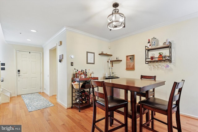 dining space featuring light wood finished floors, crown molding, a chandelier, baseboards, and recessed lighting