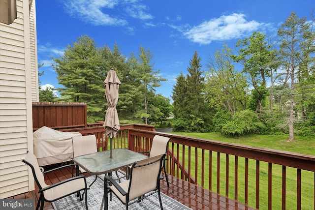 deck featuring outdoor dining area and a lawn