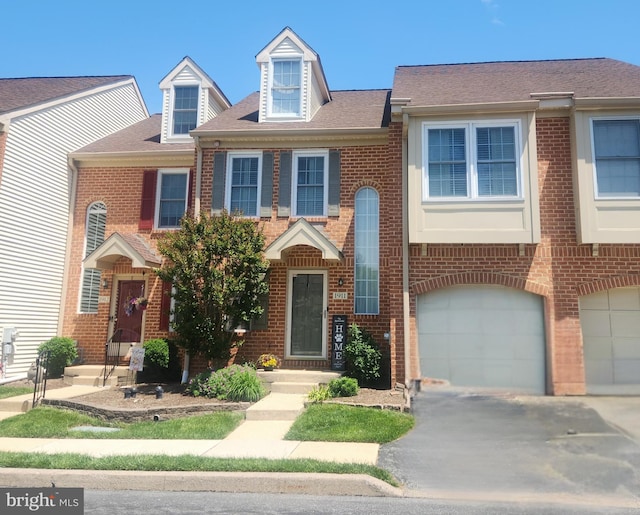 view of property featuring brick siding, driveway, and a garage