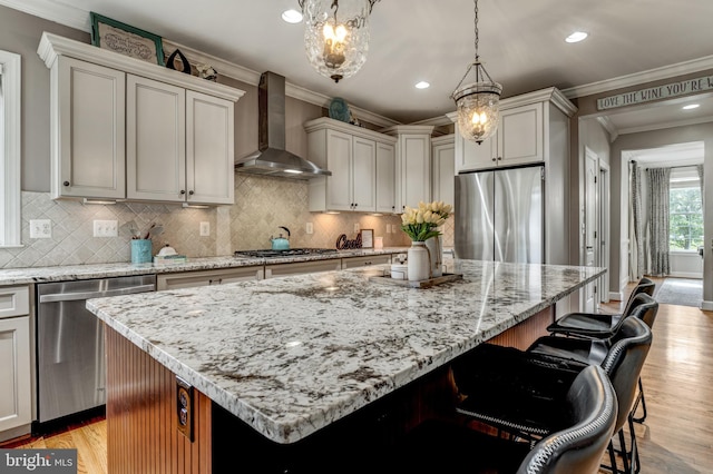 6034 Franconia Rd, Alexandria, VA 22310 - kitchen featuring appliances with stainless steel finishes, wall chimney exhaust hood, a center island, light wood-style flooring, and crown molding