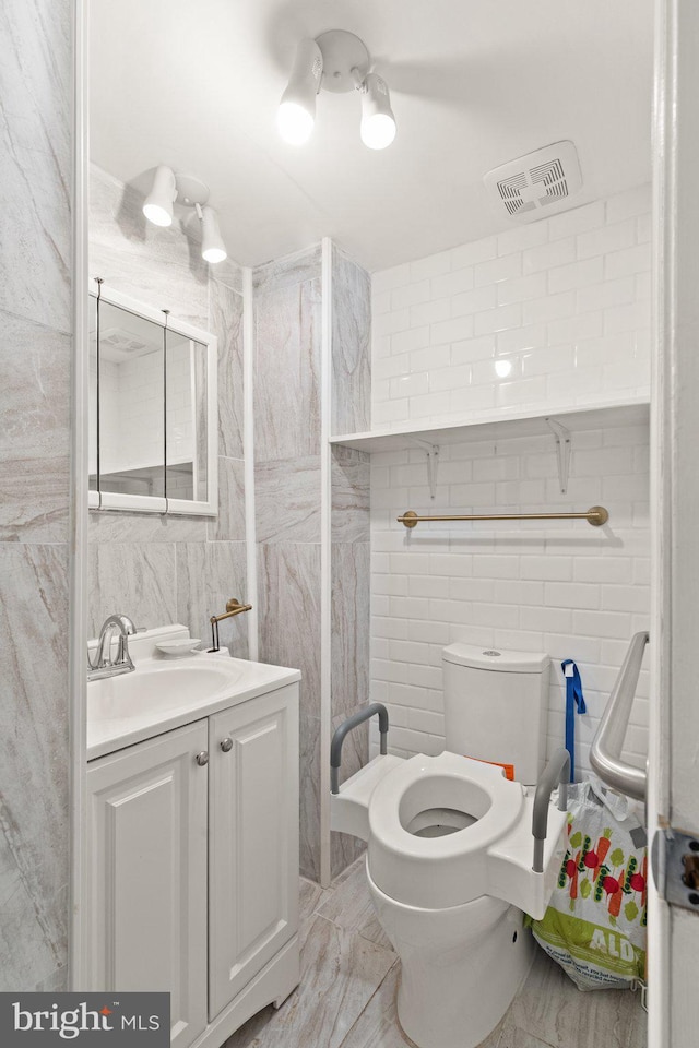 312 S Wolfe St, Baltimore, MD 21231 - bathroom featuring tile walls, marble finish flooring, toilet, and vanity