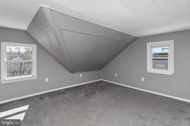 additional living space featuring lofted ceiling, healthy amount of natural light, carpet flooring, and baseboards