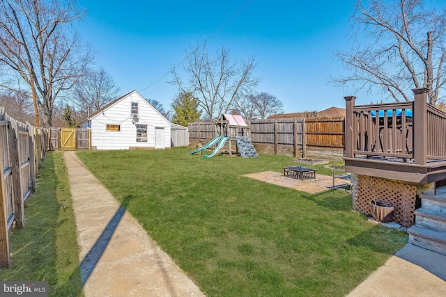 view of yard featuring a fire pit, a playground, and a deck