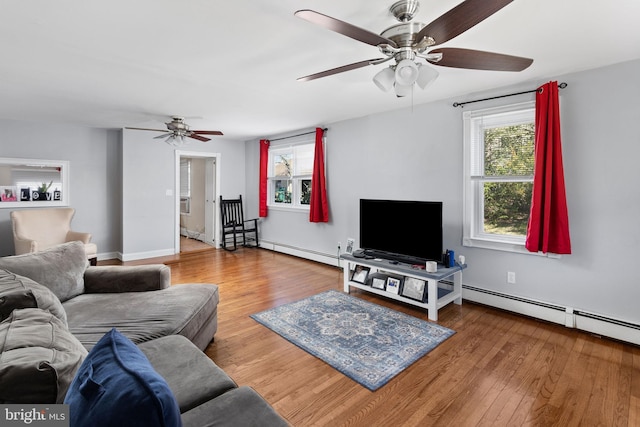 living area with ceiling fan, a baseboard heating unit, wood finished floors, and baseboards