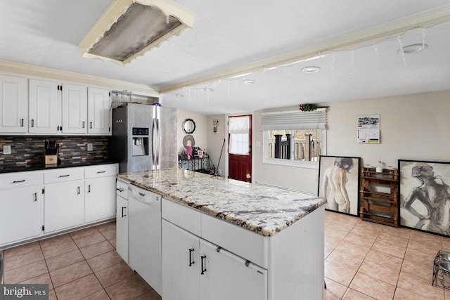 kitchen featuring stainless steel refrigerator with ice dispenser, dishwasher, light tile patterned flooring, a kitchen island, and decorative backsplash