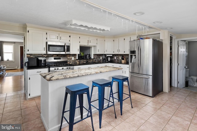kitchen with stainless steel appliances, light tile patterned floors, ornamental molding, a center island, and tasteful backsplash