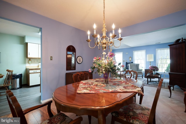 dining space with a chandelier, light wood finished floors, and baseboards