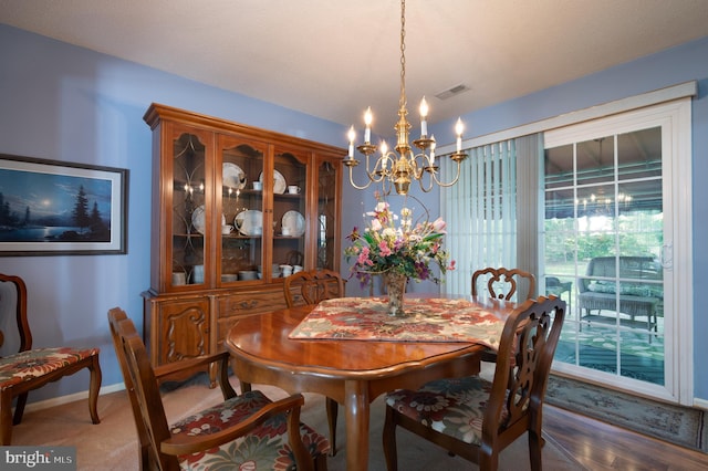 carpeted dining space with a chandelier and baseboards
