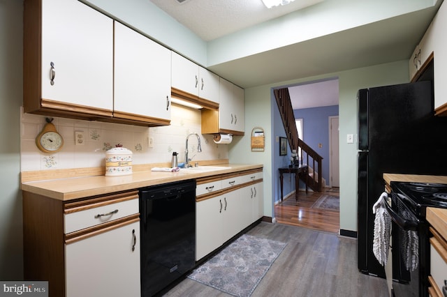 kitchen with black appliances, a sink, dark wood-style flooring, and tasteful backsplash