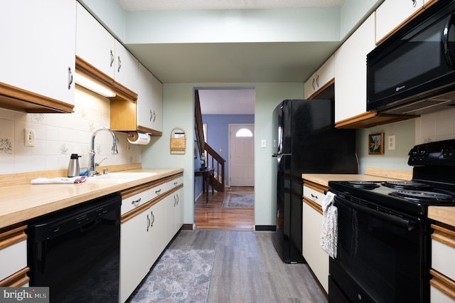 kitchen with black appliances, a sink, light countertops, dark wood finished floors, and white cabinets