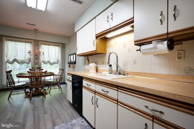 kitchen featuring a sink, dishwasher, white cabinetry, light countertops, and wood finished floors