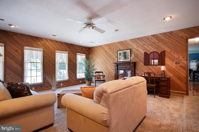 living area with carpet flooring, a ceiling fan, a textured ceiling, wood walls, and recessed lighting