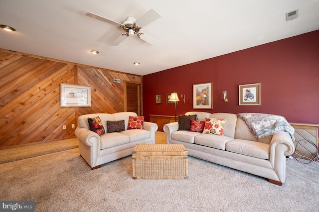 carpeted living room featuring wooden walls, a ceiling fan, an accent wall, and recessed lighting