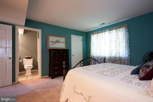 bedroom with light colored carpet, ensuite bath, and baseboards