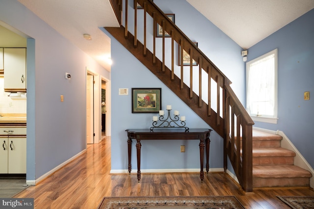 staircase featuring wood finished floors and baseboards