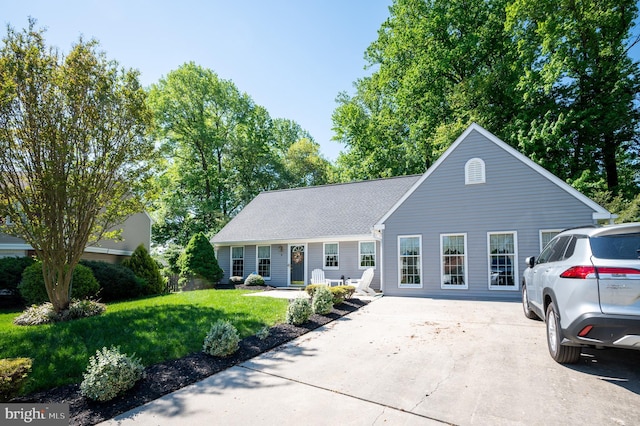 view of front of home with driveway, a front yard, and roof with shingles