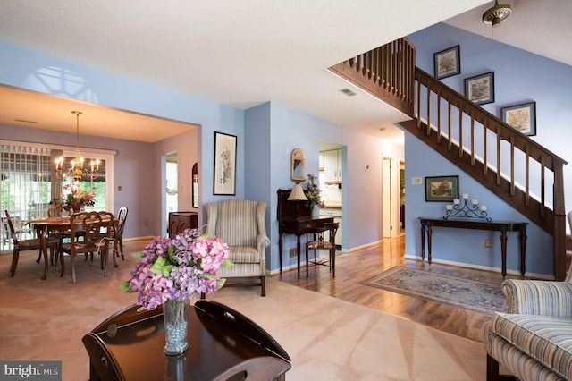 carpeted living room with a chandelier, stairs, wood finished floors, and baseboards
