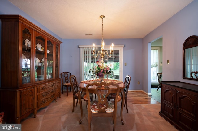 dining room with a chandelier, light carpet, and baseboards