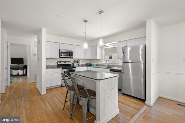 2112 Wittington Blvd, Alexandria, VA 22308 - kitchen featuring appliances with stainless steel finishes, a sink, light wood finished floors, white cabinets, and a center island
