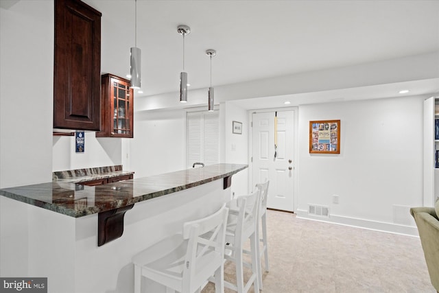 2112 Wittington Blvd, Alexandria, VA 22308 - kitchen featuring dark stone countertops, a kitchen bar, glass insert cabinets, recessed lighting, and a peninsula