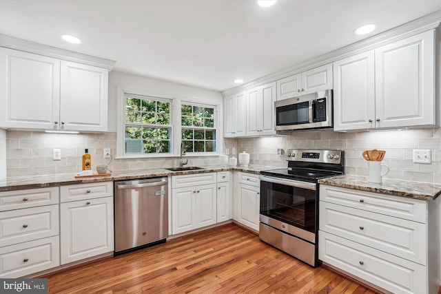 5938 New England Woods Dr, Burke, VA 22015 - kitchen with stainless steel appliances, light wood-style floors, white cabinetry, backsplash, and light stone counters