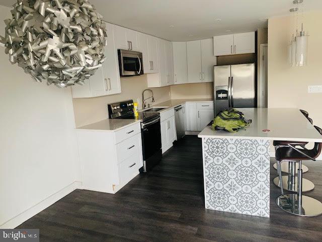 12001 Old Columbia Pike Unit 12001, Silver Spring, MD 20904 - kitchen featuring appliances with stainless steel finishes, a sink, a kitchen bar, and dark wood finished floors