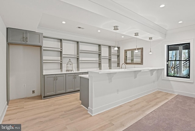 1564 Forest Villa Ln, Mclean, VA 22101 - kitchen with gray cabinetry, a peninsula, light wood-style flooring, a breakfast bar area, and hanging light fixtures