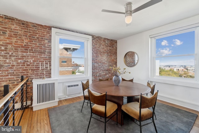 1901 Columbia Rd NW Unit 805, Washington, DC 20009 - dining room featuring wood finished floors, brick wall, ceiling fan, a wall mounted air conditioner, and radiator heating unit