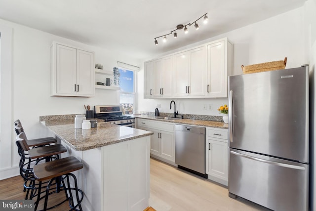 1901 Columbia Rd NW Unit 805, Washington, DC 20009 - kitchen with stainless steel appliances, a sink, light wood-style flooring, a peninsula, and a breakfast bar