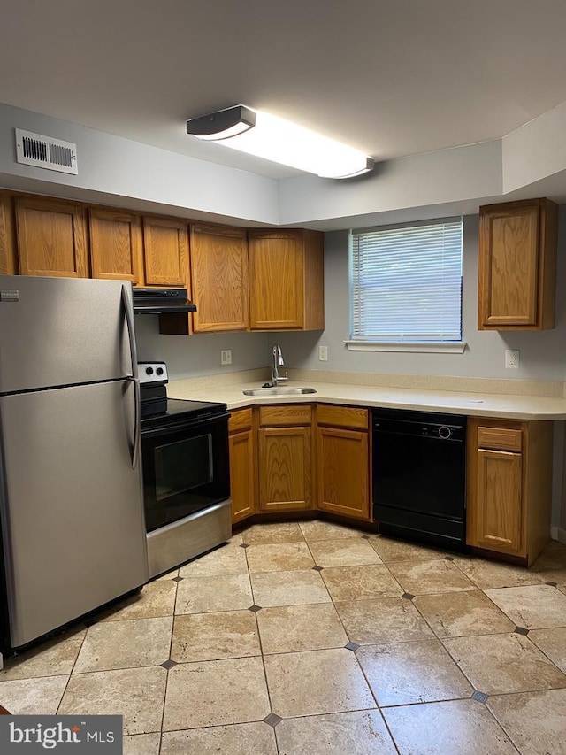 kitchen featuring appliances with stainless steel finishes, a sink, brown cabinetry, and light countertops