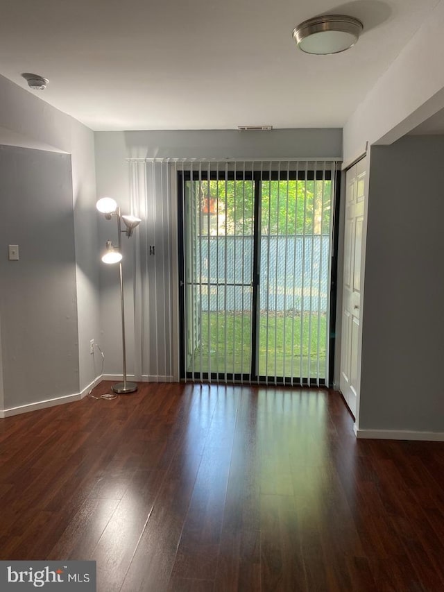 empty room featuring wood finished floors, baseboards, and a smoke detector