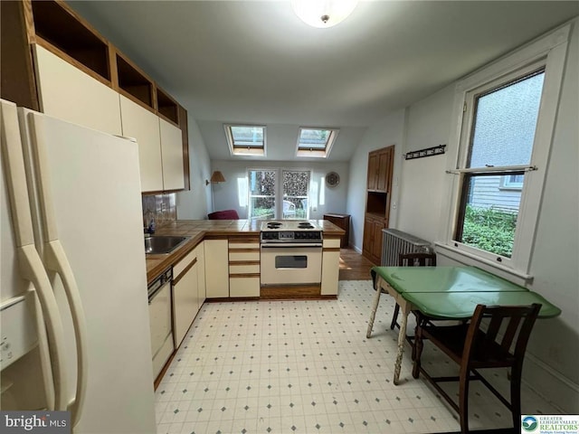 35 W Broadway, Jim Thorpe, PA 18229 - kitchen with white appliances, a peninsula, a sink, tile countertops, and a skylight