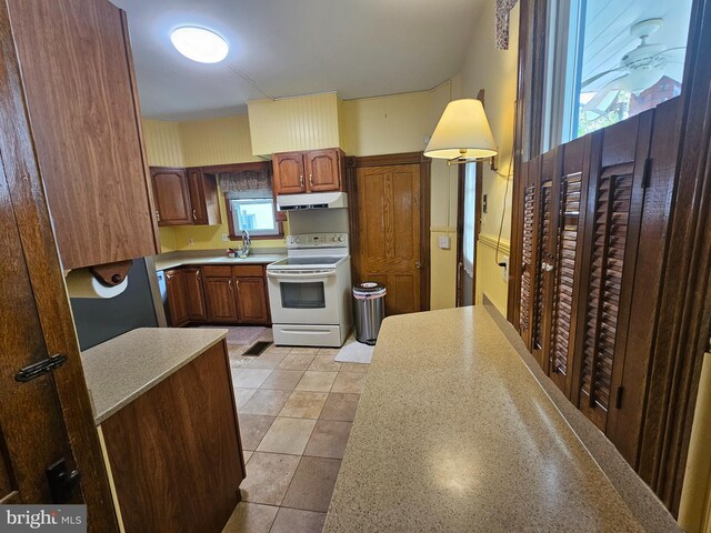 304 Pulaski St, Cumberland, MD 21502 - kitchen with white range with electric stovetop, under cabinet range hood, a sink, light countertops, and brown cabinets