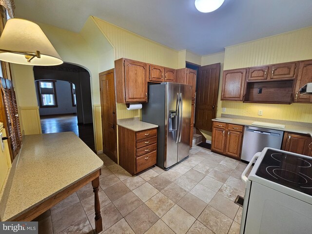304 Pulaski St, Cumberland, MD 21502 - kitchen featuring appliances with stainless steel finishes, light countertops, arched walkways, and brown cabinets
