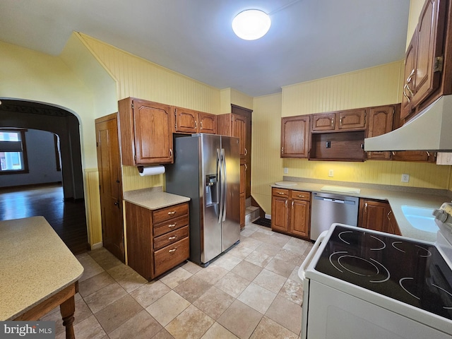 304 Pulaski St, Cumberland, MD 21502 - kitchen with appliances with stainless steel finishes, under cabinet range hood, light countertops, brown cabinetry, and arched walkways