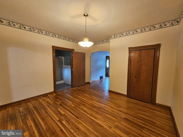 304 Pulaski St, Cumberland, MD 21502 - unfurnished dining area featuring arched walkways, dark wood-style flooring, and baseboards