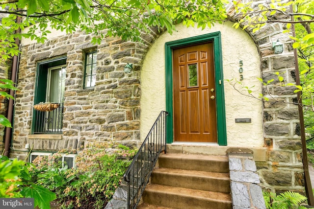 view of exterior entry with stone siding and stucco siding