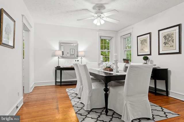 dining space with light wood-style flooring, ceiling fan, a textured ceiling, and baseboards